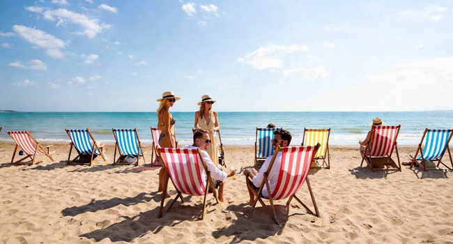 Participantes adultos relajándose en tumbonas en la playa de Bournemouth durante un viaje de idiomas con LISA! en Inglaterra