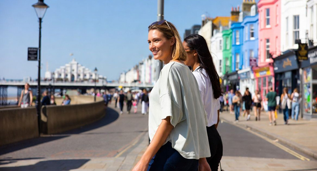 Participantes caminando por el paseo marítimo de Brighton con casas coloridas durante un viaje de idiomas con LISA! en Inglaterra