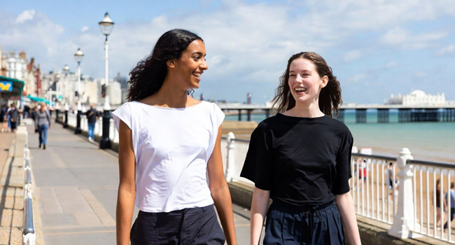 Dos participantes caminando por el paseo marítimo junto al muelle en Brighton durante un viaje de idiomas con LISA! en Inglaterra