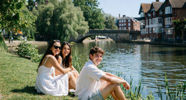 Viajes de idiomas en Inglaterra Cambridge City con LISA! – ocio, sol y momentos de relax junto al río Adultos participantes de un viaje de idiomas con LISA! en Cambridge City Inglaterra sentados junto al río disfrutando del sol y el tiempo libre
