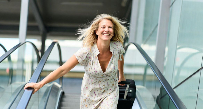  Adulta con maleta en el aeropuerto durante unas vacaciones educativas con LISA! emocionada por viajar a Malta para aprender inglés