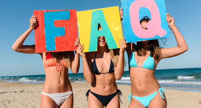 Participantes adultas en un viaje de idiomas en Malta en la playa con carteles de preguntas frecuentes y respuestas