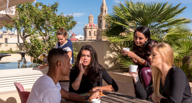 Viajes de idiomas en Malta para adultos con terraza en la azotea en Sliema Participantes de un viaje de idiomas para adultos en Malta en la terraza de la azotea de la escuela de idiomas en Sliema con vista a la ciudad
