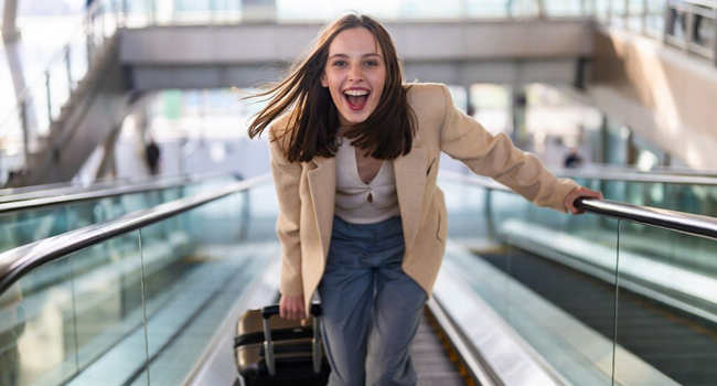 Vacaciones educativas Quebec Canadá con LISA! – aprender francés y viajar con tranquilidad Joven con maleta en el aeropuerto durante unas vacaciones educativas con LISA! emocionada por viajar a Quebec para aprender francés