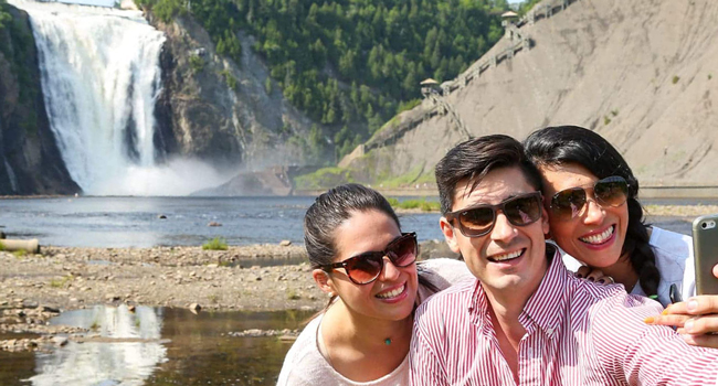 Vacaciones educativas Quebec Canadá con LISA! – aprender francés y disfrutar experiencias en la naturaleza Adultos haciéndose un selfie frente a una cascada en Quebec durante unas vacaciones educativas con LISA! disfrutando de la naturaleza y actividades de ocio