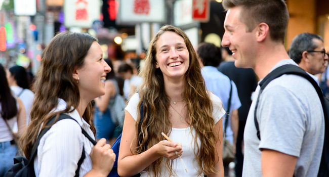 Vacaciones educativas Osaka Japón con LISA! – aprender japonés, hacer nuevos amigos y vivir experiencias inolvidables Adultos riendo juntos en Osaka durante unas vacaciones educativas con LISA! disfrutando de la vida urbana internacional y aprendiendo japonés
