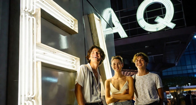 Jóvenes adultos frente a un letrero luminoso FAQ en Tokio durante un viaje de idiomas con LISA! disfrutando de la vida nocturna