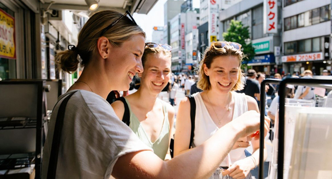 Adultos comprando comida callejera en Tokio durante un viaje de idiomas con LISA! descubriendo especialidades locales y cultura