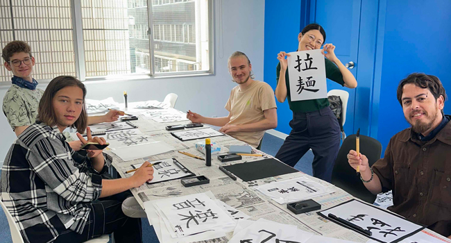 Adultos aprendiendo caracteres japoneses en un curso en Tokio durante un viaje de idiomas con LISA! practicando caligrafía