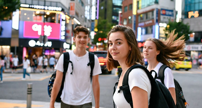  Jóvenes adultos cruzando la calle en Seúl Hongdae durante un viaje de idiomas con LISA! disfrutando de la vida urbana