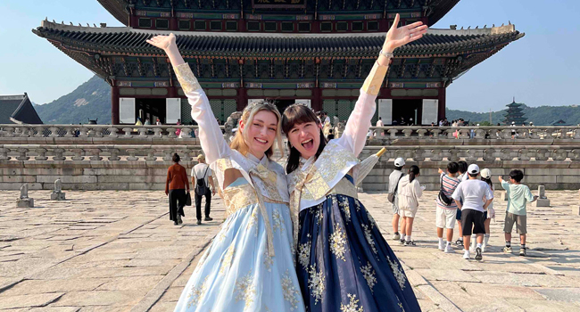 Adultos con ropa tradicional coreana frente a un templo en Seúl durante un viaje de idiomas con LISA! viviendo la cultura