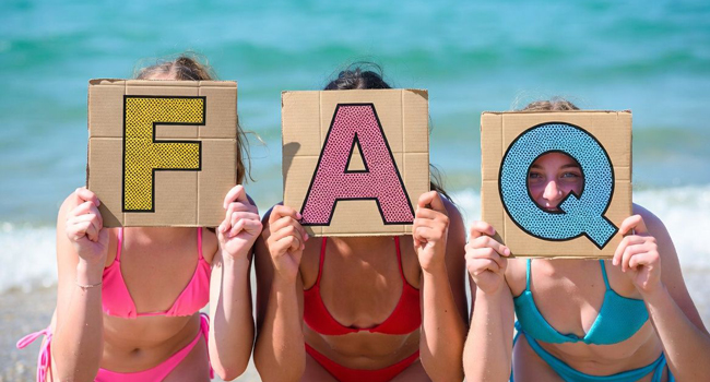 Preguntas frecuentes LISA! viajes de idiomas – respuestas a preguntas comunes Tres estudiantes en la playa en Bournemouth Park Inglaterra sostienen carteles FAQ durante un viaje de idiomas con LISA!