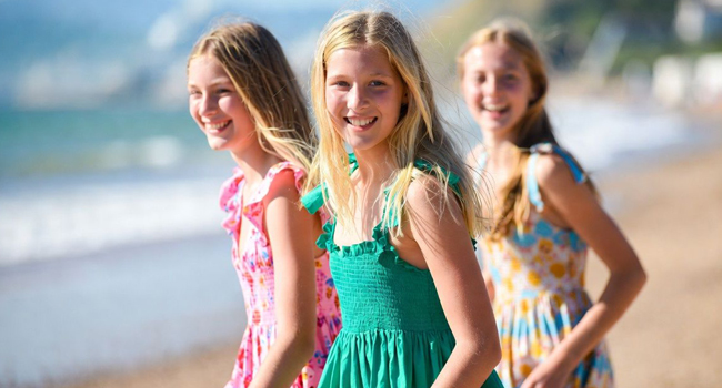 Tres estudiantes en la playa en Bournemouth Inglaterra durante un viaje de idiomas con LISA! con vestidos de verano disfrutando del mar