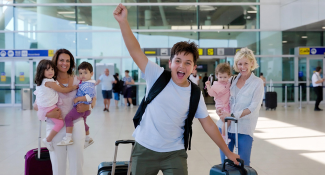 Llegada a un viaje de idiomas para estudiantes en Inglaterra Brighton con LISA! – estudiante feliz en el aeropuerto Estudiante llegando al aeropuerto con el brazo levantado emocionado por un viaje de idiomas con LISA! para estudiantes en Inglaterra Brighton