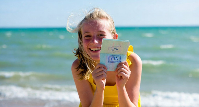 Estudiante en la playa en Exmouth durante un viaje de idiomas con LISA! mostrando documento ETA de entrada a Inglaterra