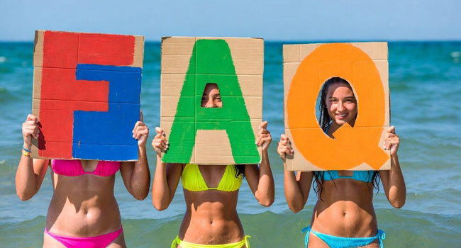  Estudiantes en la playa en Exmouth sostienen letras FAQ durante un viaje de idiomas con LISA! con el mar de fondo