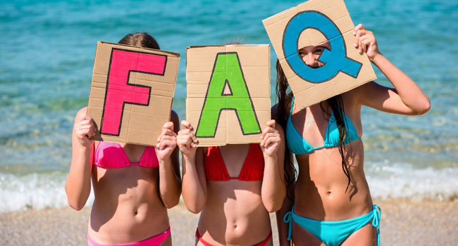  Estudiantes en la playa en Portsmouth sostienen letras FAQ durante un viaje de idiomas con LISA! con el mar de fondo