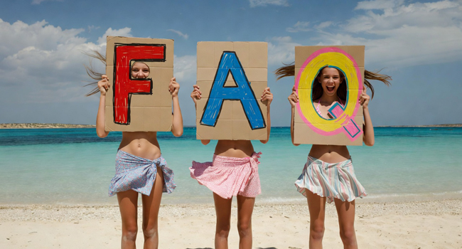 Viaje de idiomas para estudiantes en Malta: preguntas frecuentes sobre la estancia en Salina Beach Tres estudiantes de un viaje de idiomas para estudiantes en Malta en Salina Beach con grandes letras FAQ frente al mar