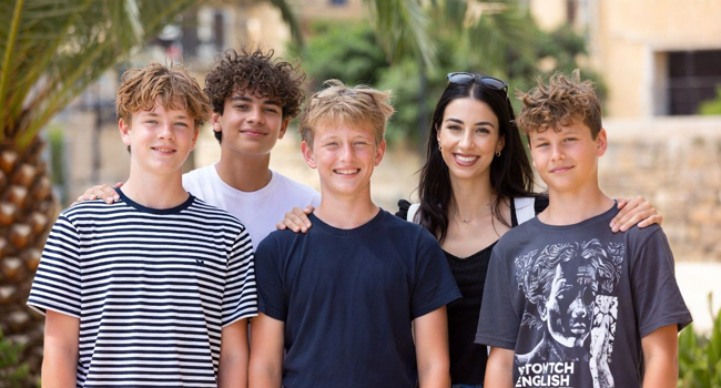 Monitora y profesora con cuatro chicos delante de una palmera en un viaje de idiomas en Malta San Gwann