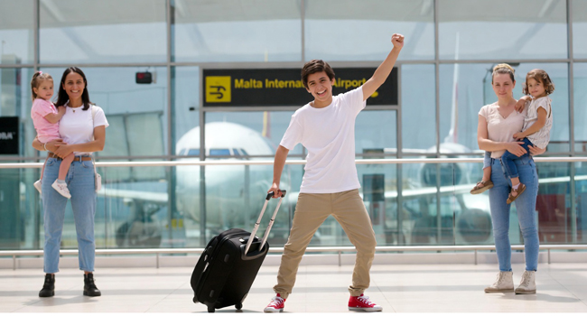 Viajes de idiomas de inglés en Malta para estudiantes con llegada a través del aeropuerto Estudiantes de un viaje de idiomas de inglés en Malta durante la llegada al aeropuerto con maleta y escena de bienvenida