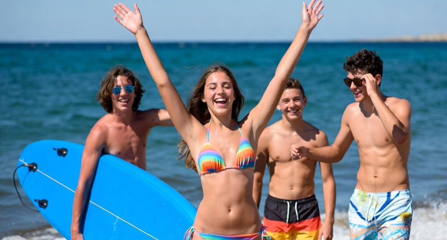 Estoy aquí, mamá: llegada a un viaje de idiomas en Malta con LISA! Chica levanta los brazos con tres chicos y el mar de fondo