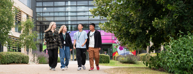 Schüler auf einem modernen Campus während einer LISA! Sprachreise in Bath Vier junge Schüler spazieren auf einem modernen Campusgelände mit Glasfassade und Gartenanlage während einer LISA! Sprachreise in Bath