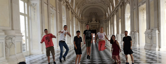 Sprachreisen Italienisch in Turin Mehrere Menschen springen freudig in einem barocken Saal bei einer LISA! Sprachreise in Turin