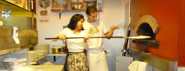 Pizza backen in Turin – Sprachreisen Italienisch Ein Pizziolo erklärt einer Frau, wie man eine Pizza in einem Holzofen backt, während einer LISA! Sprachreise Italienisch