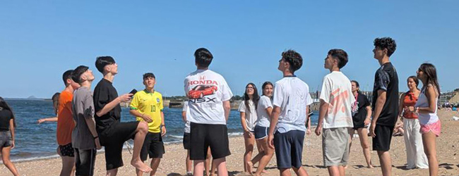 Jugendliche stehen am Strand und spielen Ball bei einer Sprachreise nach Edinburgh