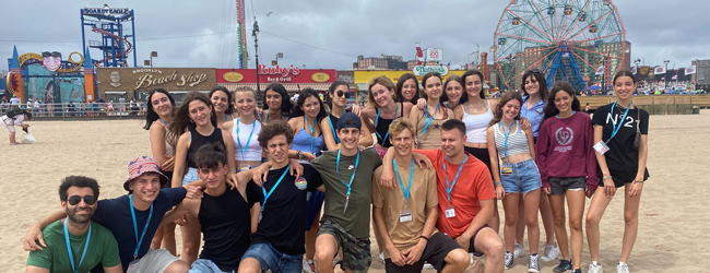 Ausflug in New York zum Strand bei einer Schülersprachreise Eine Schülergruppe steht am Strand vor Fahrgeschäften eines Freizeitparks in New York